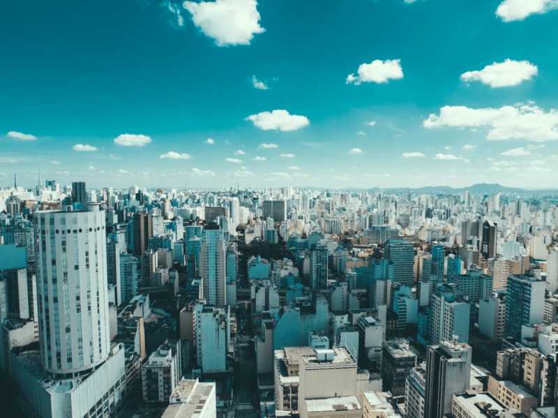 A vast cityscape under a bright blue sky with scattered clouds.