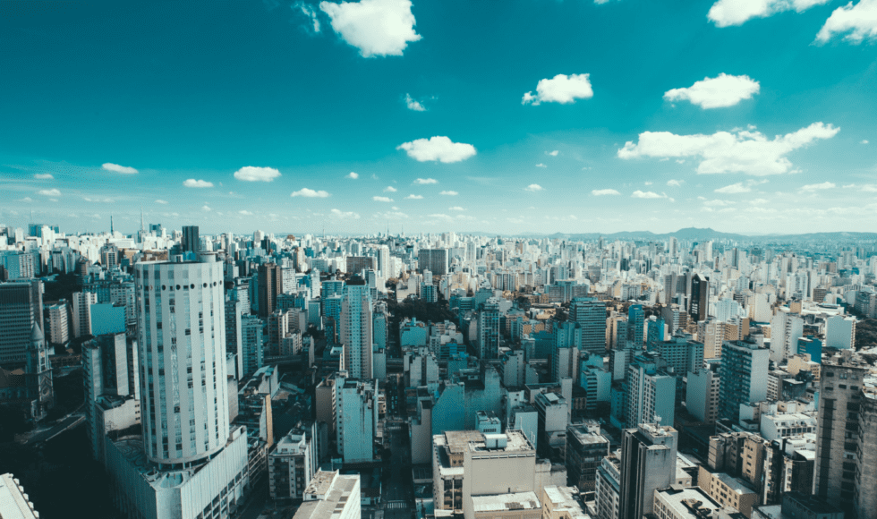 A vast cityscape under a bright blue sky with scattered clouds.