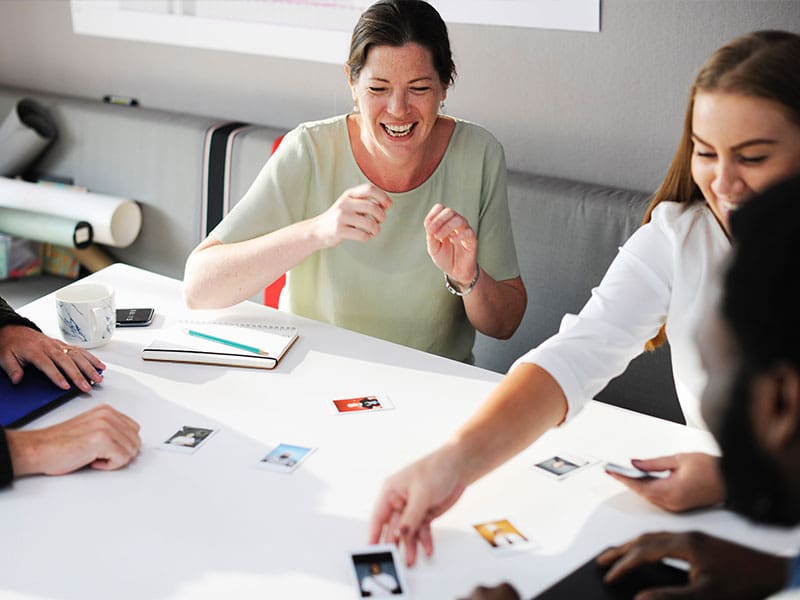 Colleagues sharing a joyful moment while sorting photos at a table.
