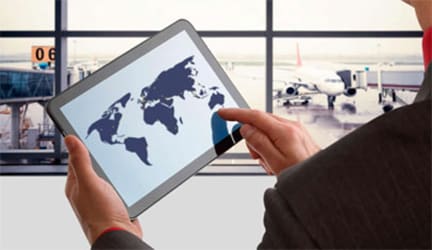 Person using a tablet with a world map at an airport terminal.