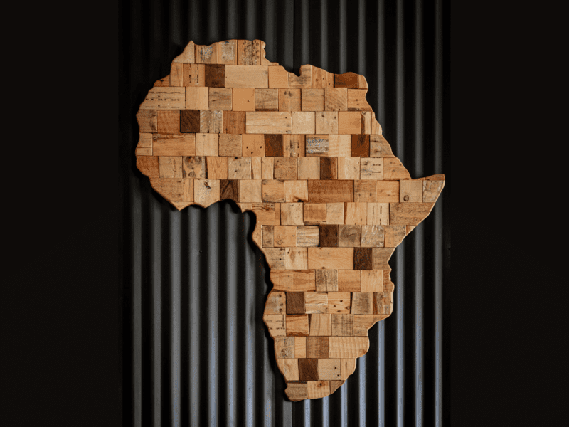 Wooden art piece shaped like the African continent on a dark background.