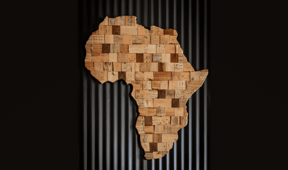 Wooden art piece shaped like the African continent on a dark background.