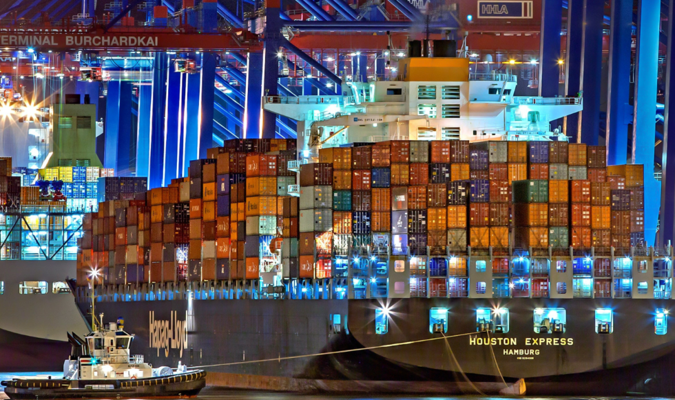 Cargo ship loaded with colorful containers docked at night.
