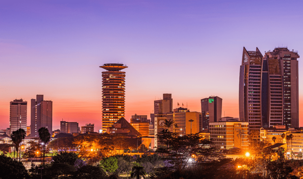 City skyline at sunset with illuminated buildings and a twilight sky.