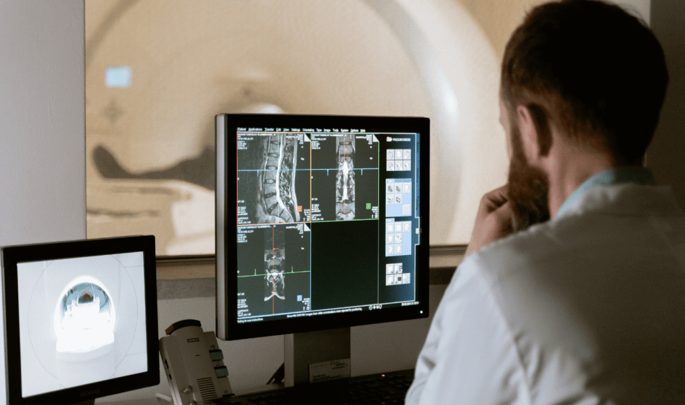 Doctor analyzing spinal X-ray images on a computer screen.