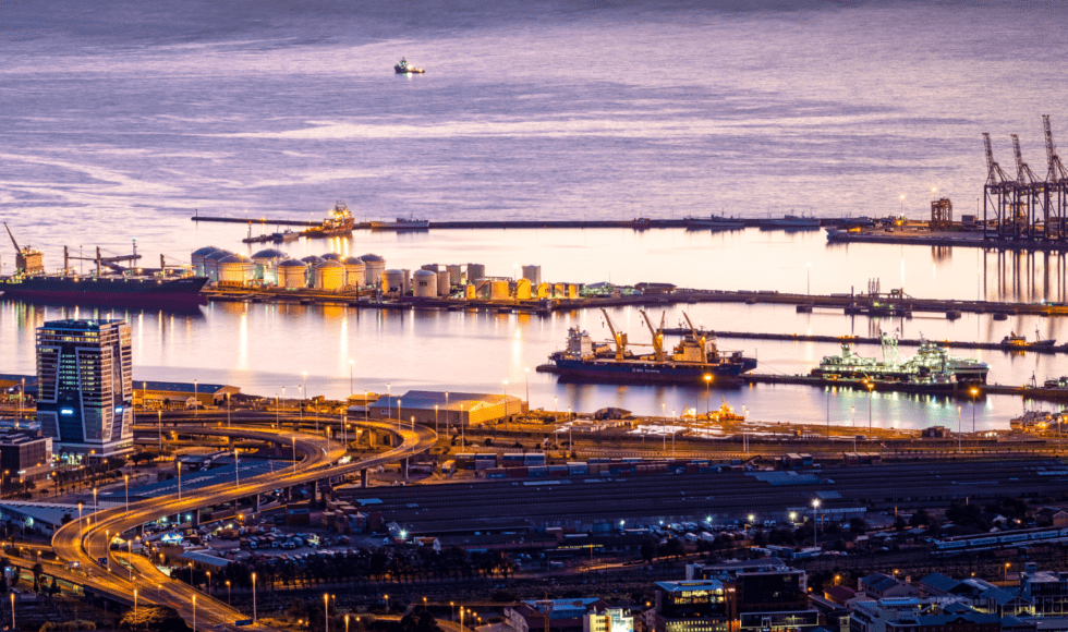 Cargo ships docked at a bustling port during sunset.