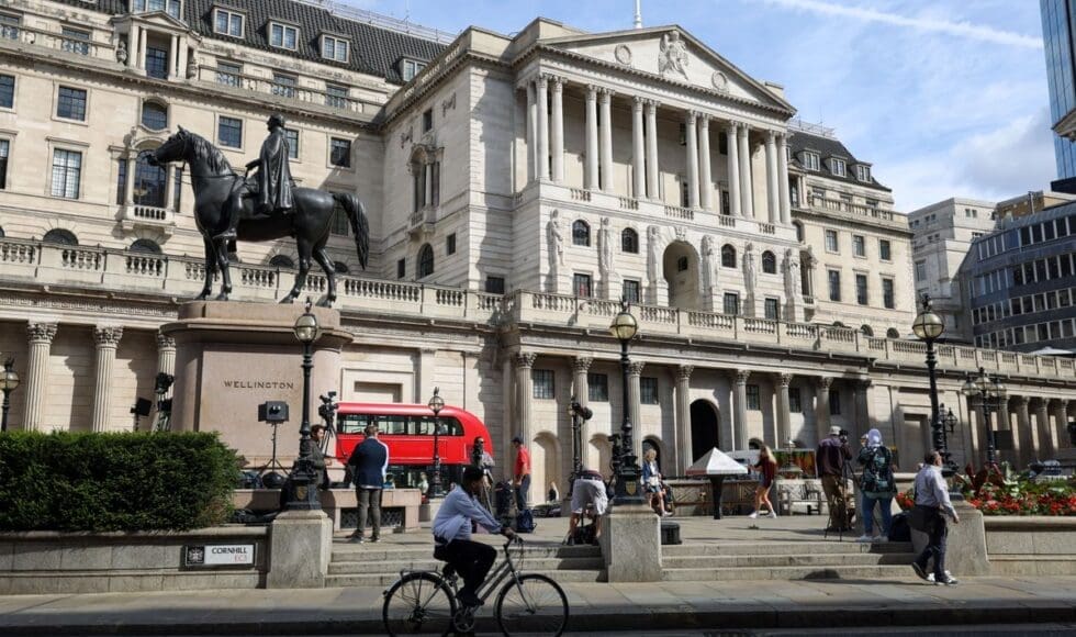 Historic building with statue, red bus, and cyclist in front.