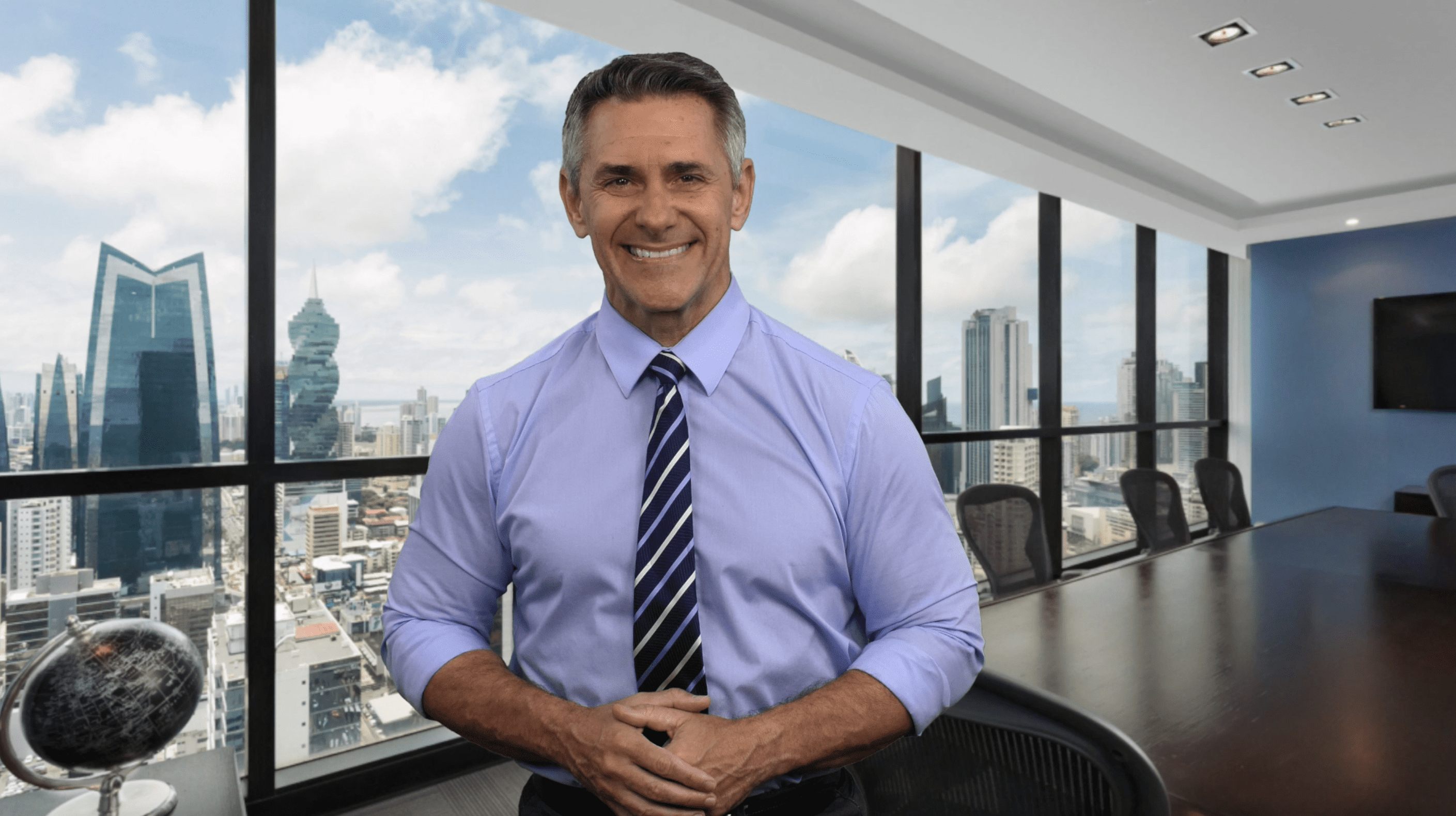A confident man in business attire smiling indoors with a cityscape background.