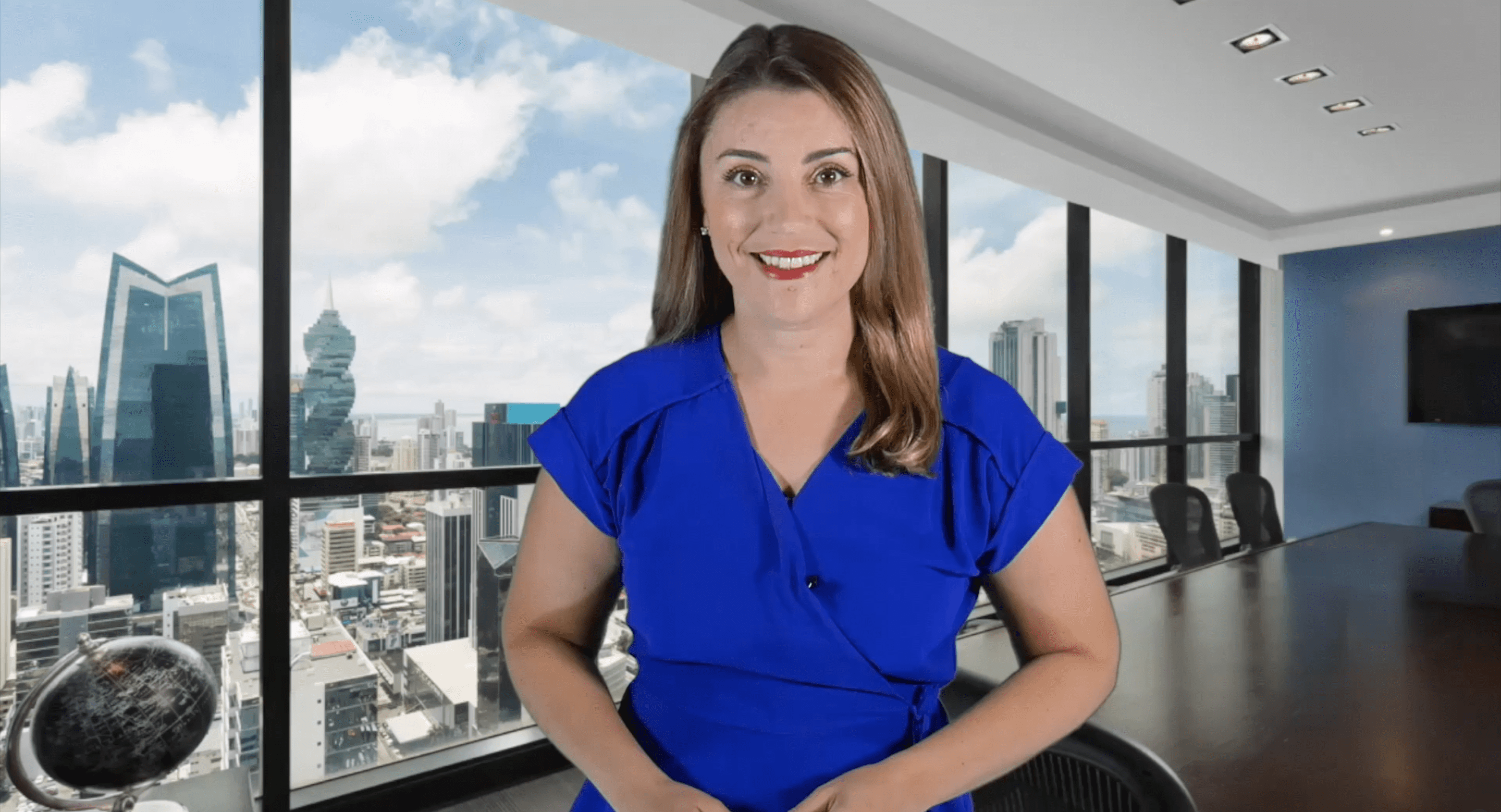 Smiling woman in blue blouse posing in a modern office with city view.