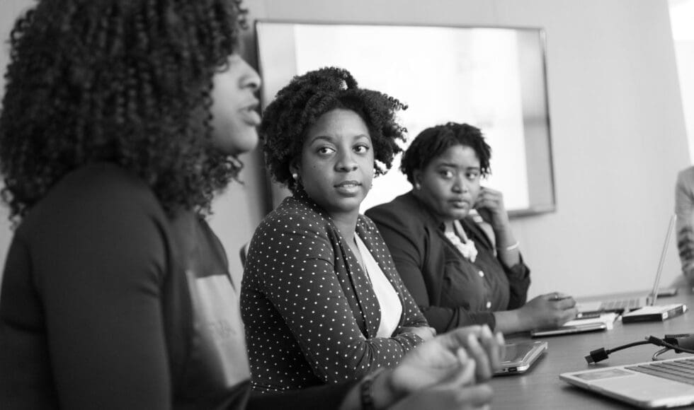 Three women engaged in a serious meeting.