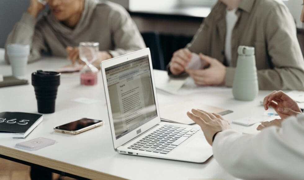 People collaborating around a laptop in a meeting.