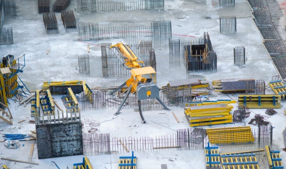 A yellow construction crane in a snowy industrial site.