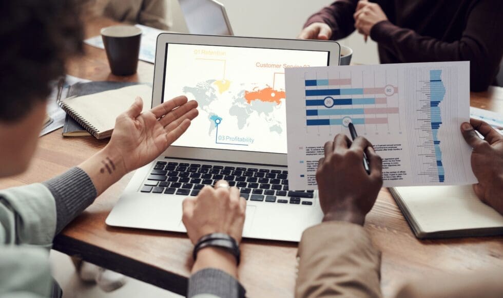 Team discussing data on a laptop with charts and maps.