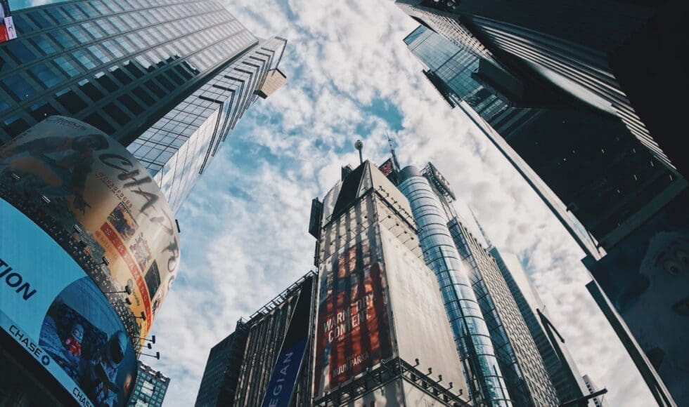 Skyward view of modern skyscrapers against a blue sky with clouds.