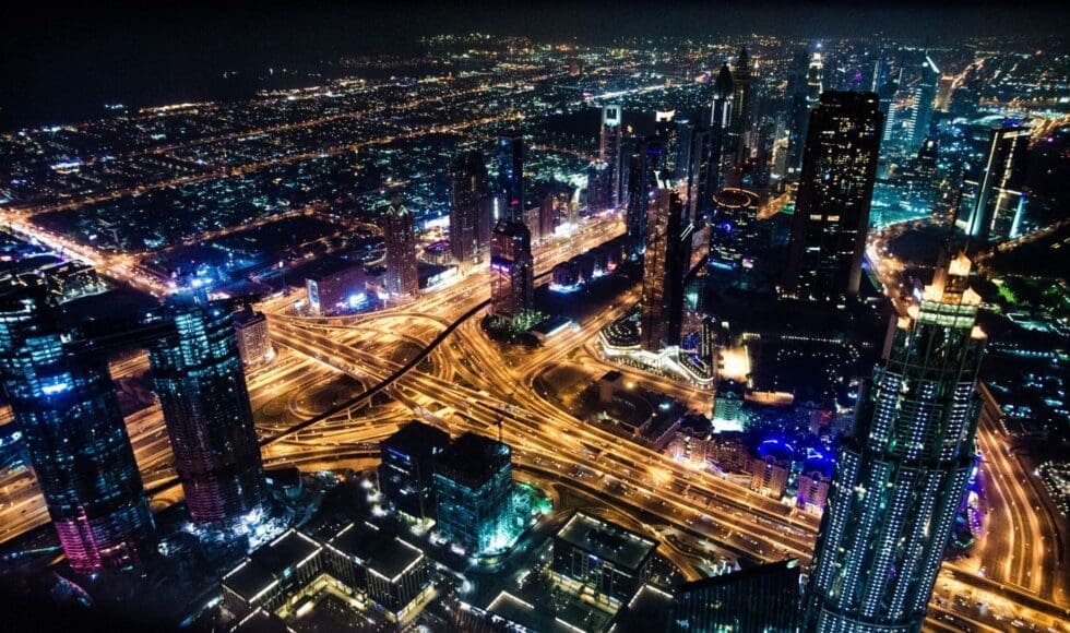 Aerial night view of a brightly lit urban highway interchange.