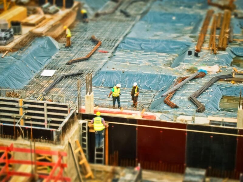 Workers in safety gear on a construction site preparing a concrete slab.