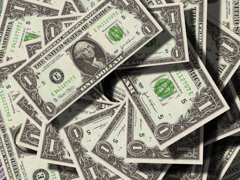 A pile of scattered one-dollar bills.