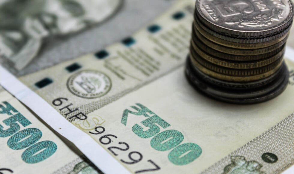 Close-up of Indian currency notes and stacked coins.