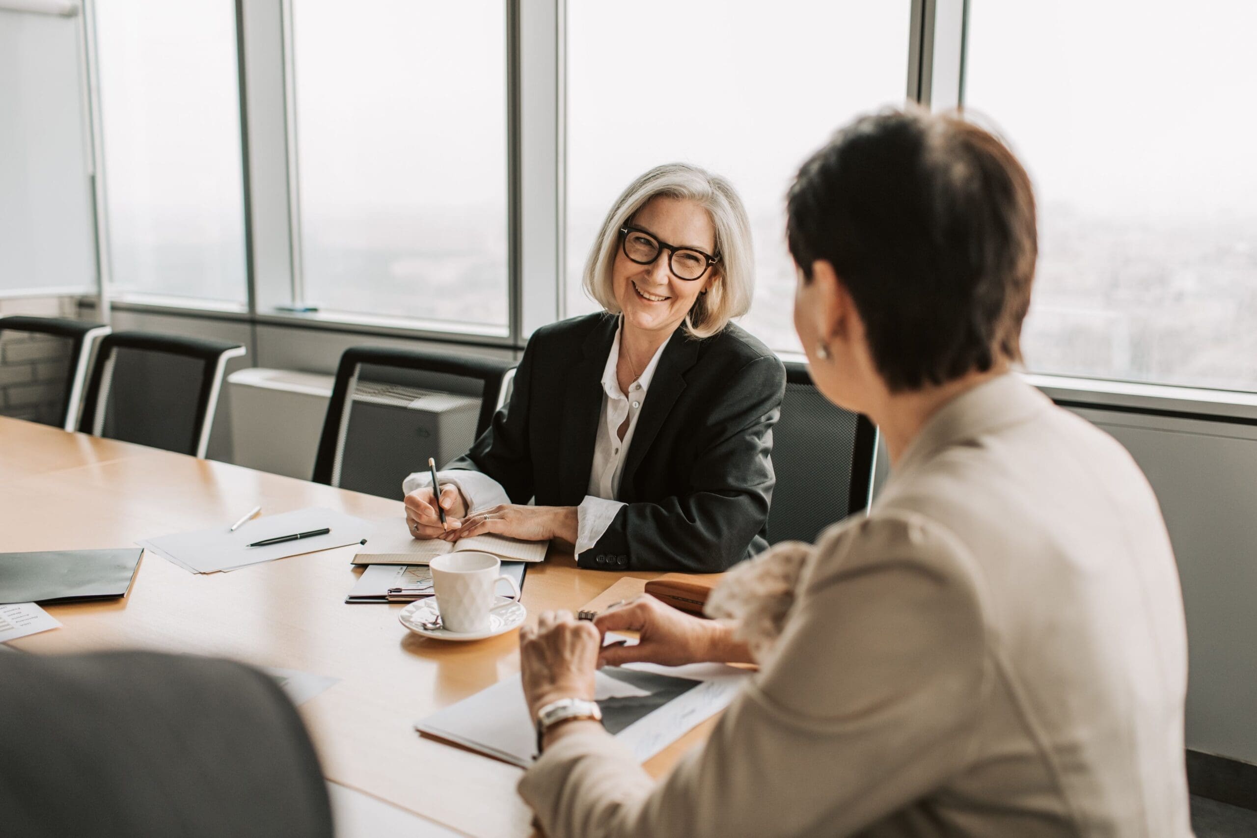 Two professional women engaged in a business conversation at a modern office.