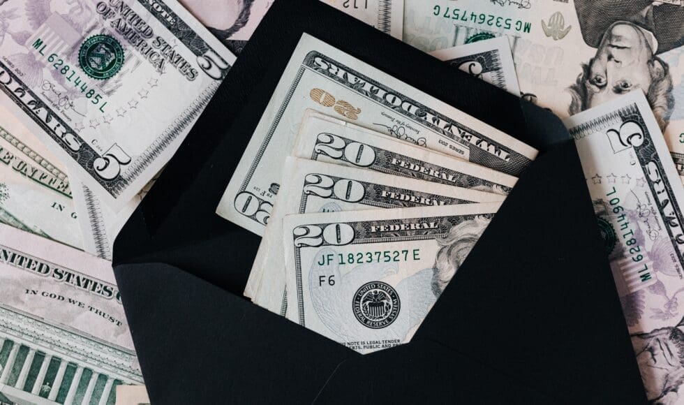 US dollar bills fanned out inside a black wallet.