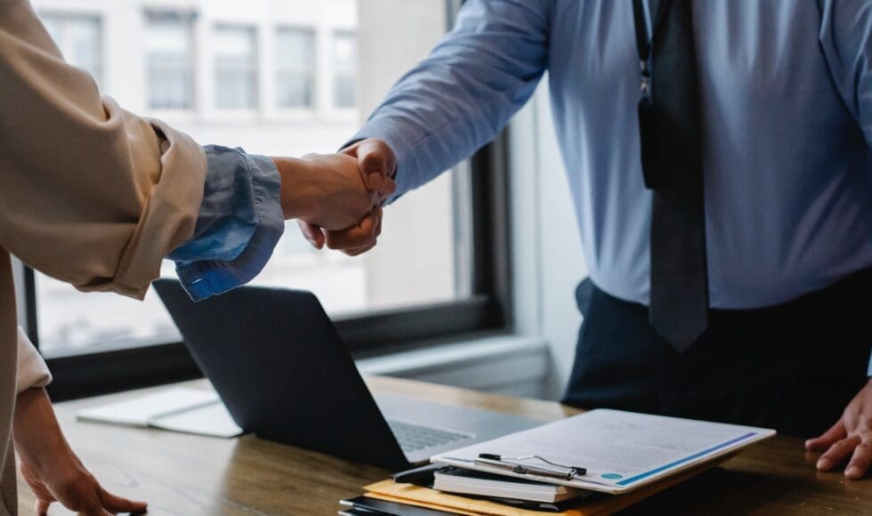 Two professionals shaking hands in an office setting.