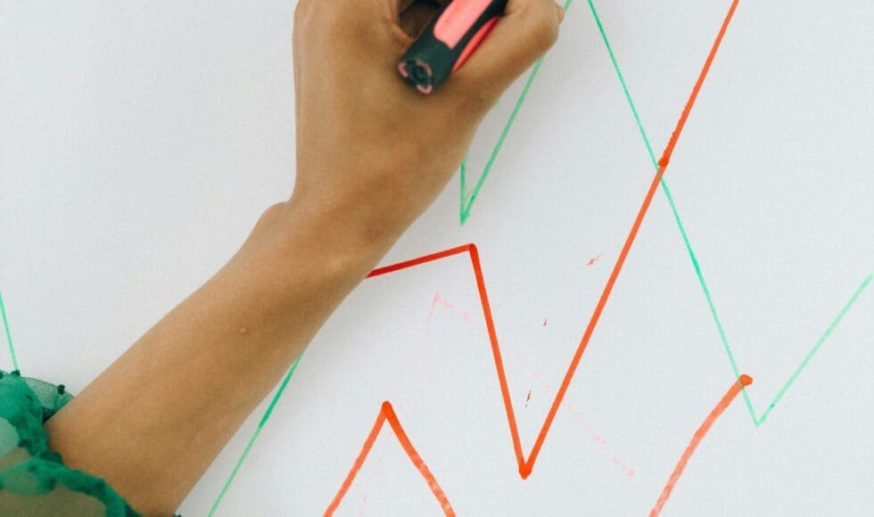 Hand drawing colorful zigzag lines on a whiteboard.
