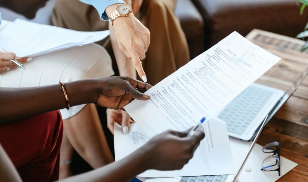 Two people reviewing documents together over a laptop.